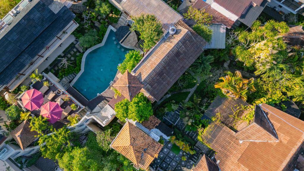 Aerial view of Home-Bience Hostel in Uluwatu - a beautiful property with a large pool area and lots of greenery