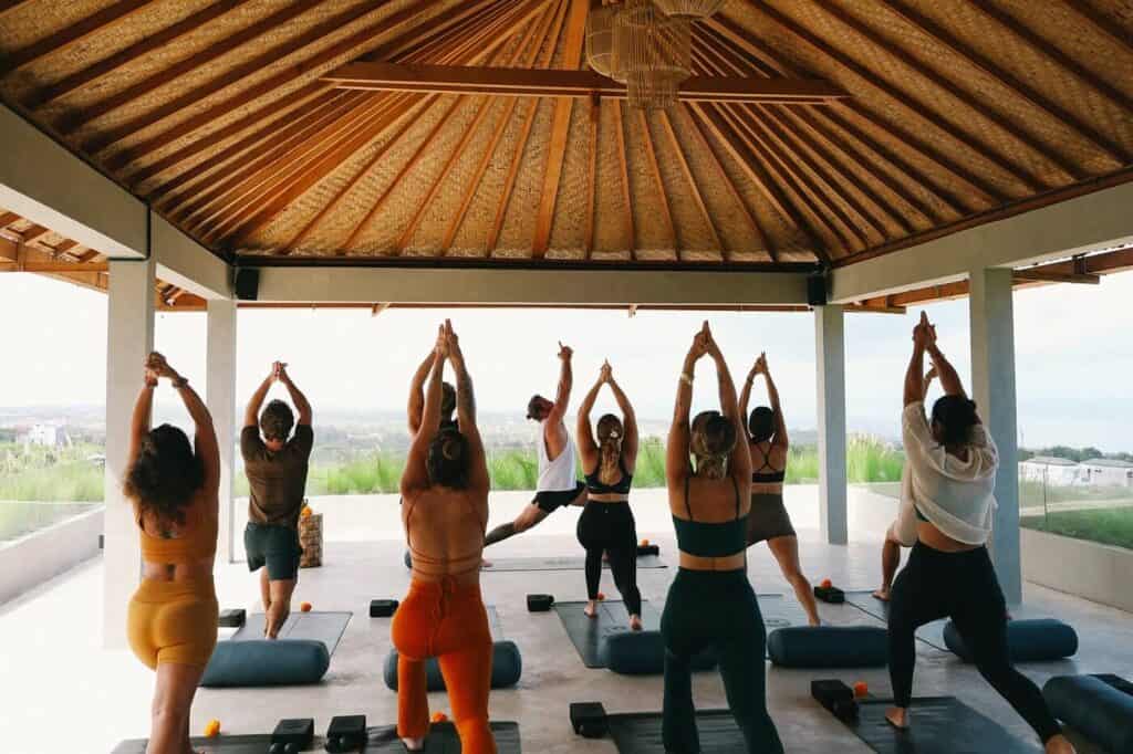 Guests practicing yoga at the rooftop Shana overlooking the ocean at Salty Prana Retreat Center in Uluwatu