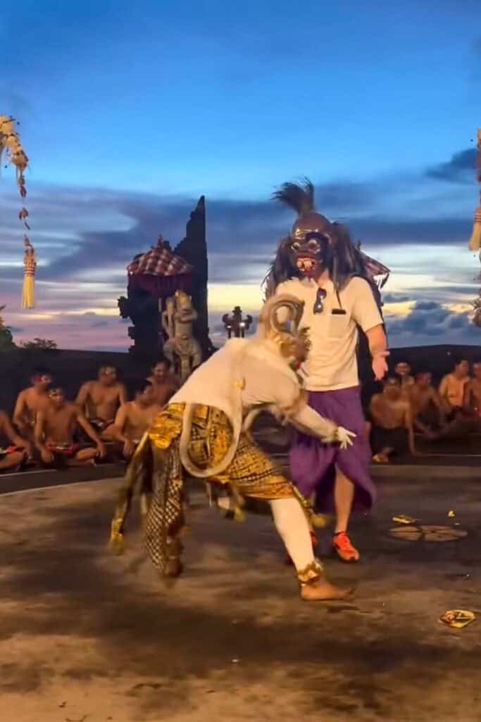 The Monkey King pulls an audience member onto stage, gives him a mask, and dances around him