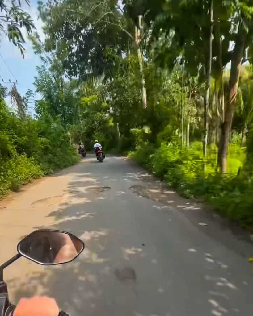 Scooters riding along a road filled with potholes in Nusa Penida, Bali