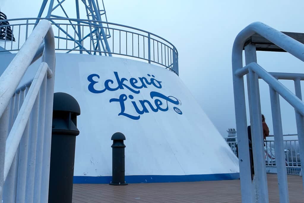 View of the upper deck on an Eckerö Line ferry, with the company logo painted on a large white funnel. Taken during a Tallinn to Helsinki ferry crossing on a foggy day.