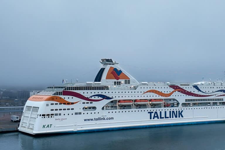 The Tallink Baltic Queen ferry docked at the port on a foggy morning, with colorful wave graphics along its side. This ship operates on the Tallinn to Helsinki ferry route.