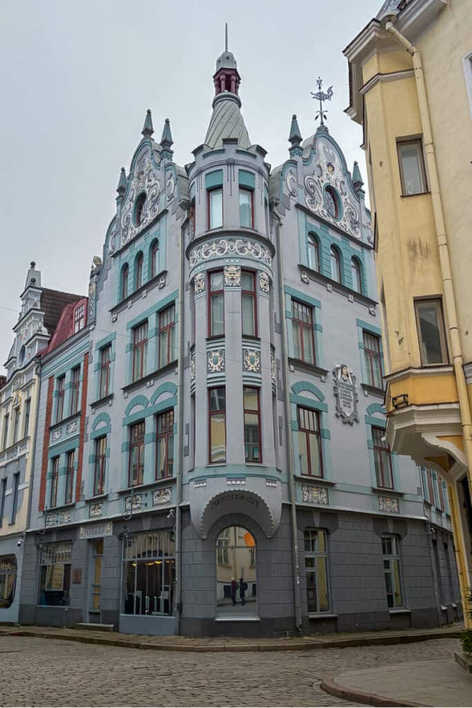 Ornate pastel Art Nouveau building along Pikk Street in Tallinn with decorative facades, arched windows, and a pointed turret rising above a cobblestone street. This historic architecture is a highlight on a one day Tallinn walking itinerary, showcasing the charm of the old town streets.