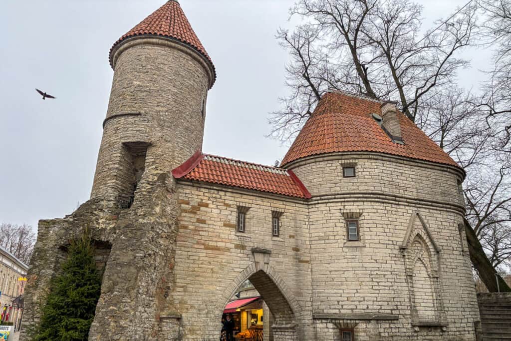 Stone towers of Viru Gate with red tiled roofs mark the entrance to Tallinn Old Town near St Catherine’s Passage, a historic landmark to pass through while in Tallinn.